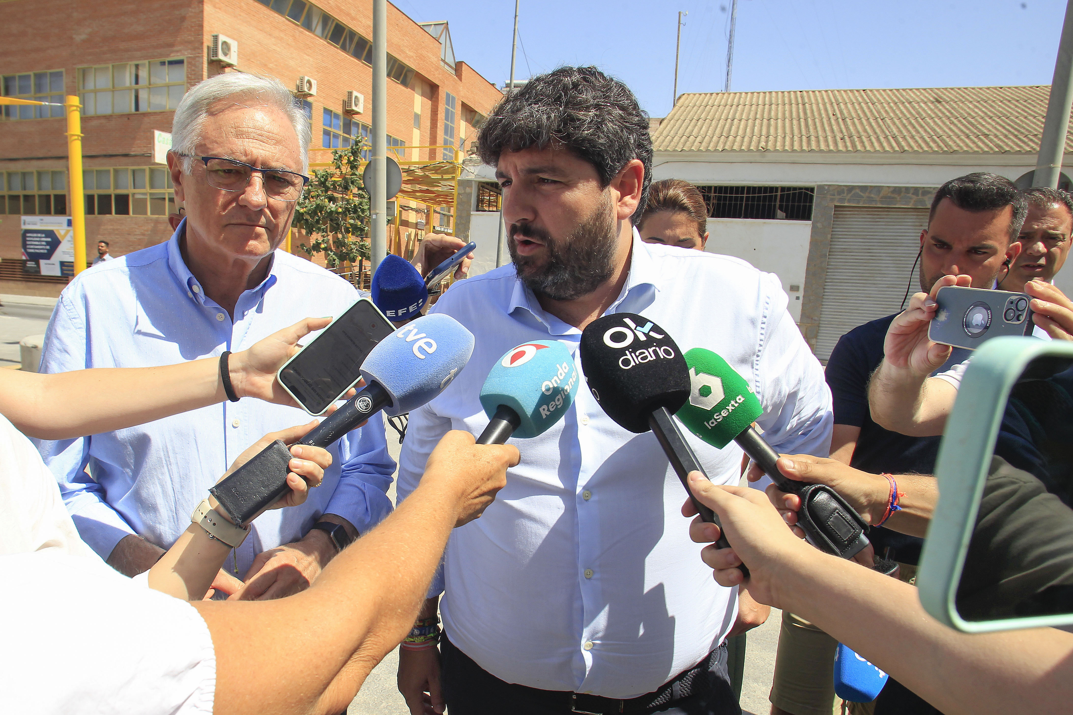 TORRE PACHECO (MURCIA), 15/07/2025.- El presidente del Gobierno de la Región de Murcia, Fernando López junto al alcalde de Torre Pacheco, Pedro Angel Roca (i), atiende a la prensa a su llegada a la región murciana este martes. López Miras ha hecho este martes un llamamiento a la calma y la convivencia pacífica, que "es lo que quieren los vecinos de Torre Pacheco", y ha reiterado la necesidad de que el Ministerio del Interior despliegue los efectivos necesarios para que "termine la violencia" y la población del Campo de Cartagena no sea esta jornada "un campo de batalla".EFE/ Morell
