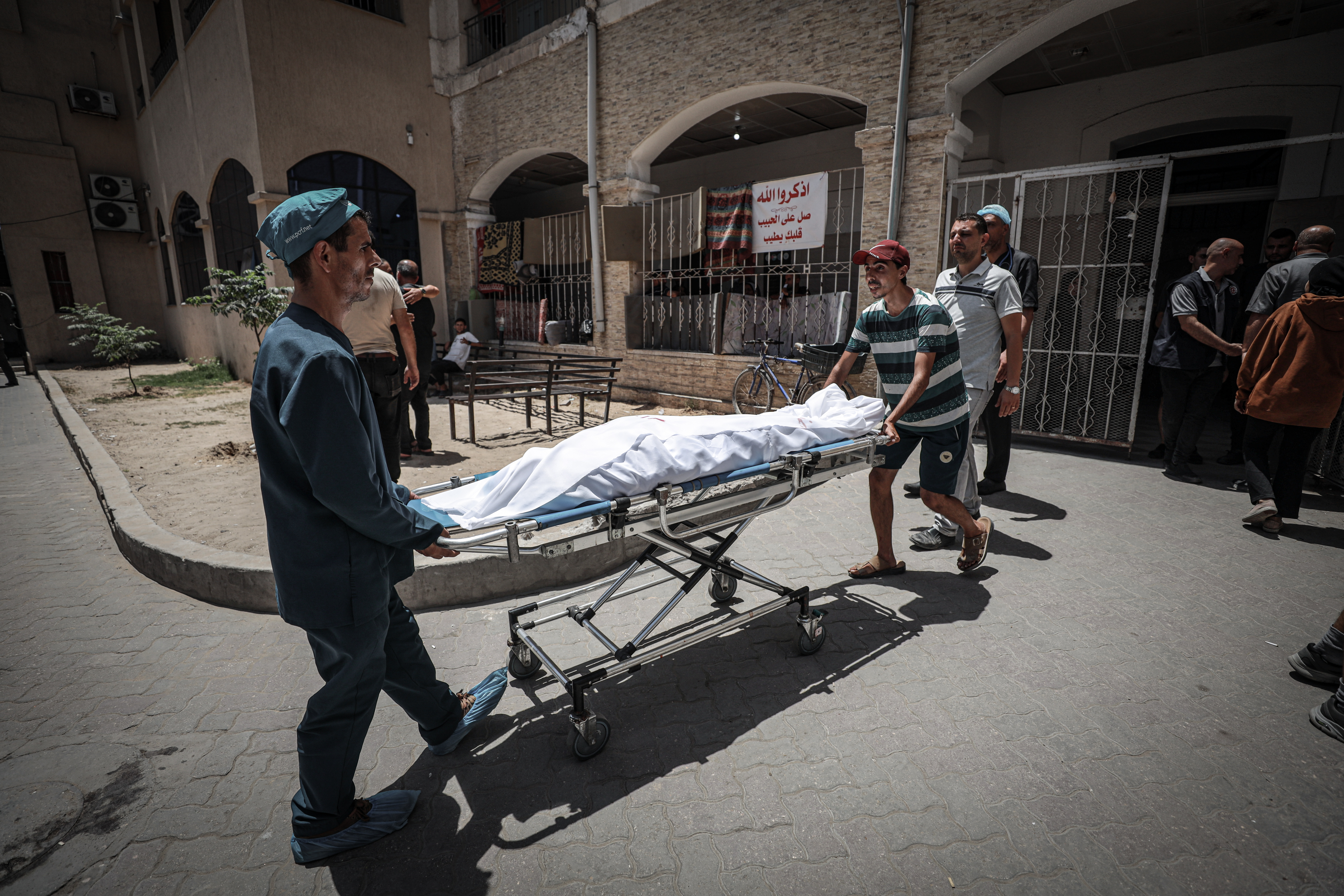 Dos hombres trasladan el cuerpo de uno de los fallecidos por el ataque israelí contra la parroquia de la Sagrada Familia de Gaza este jueves.