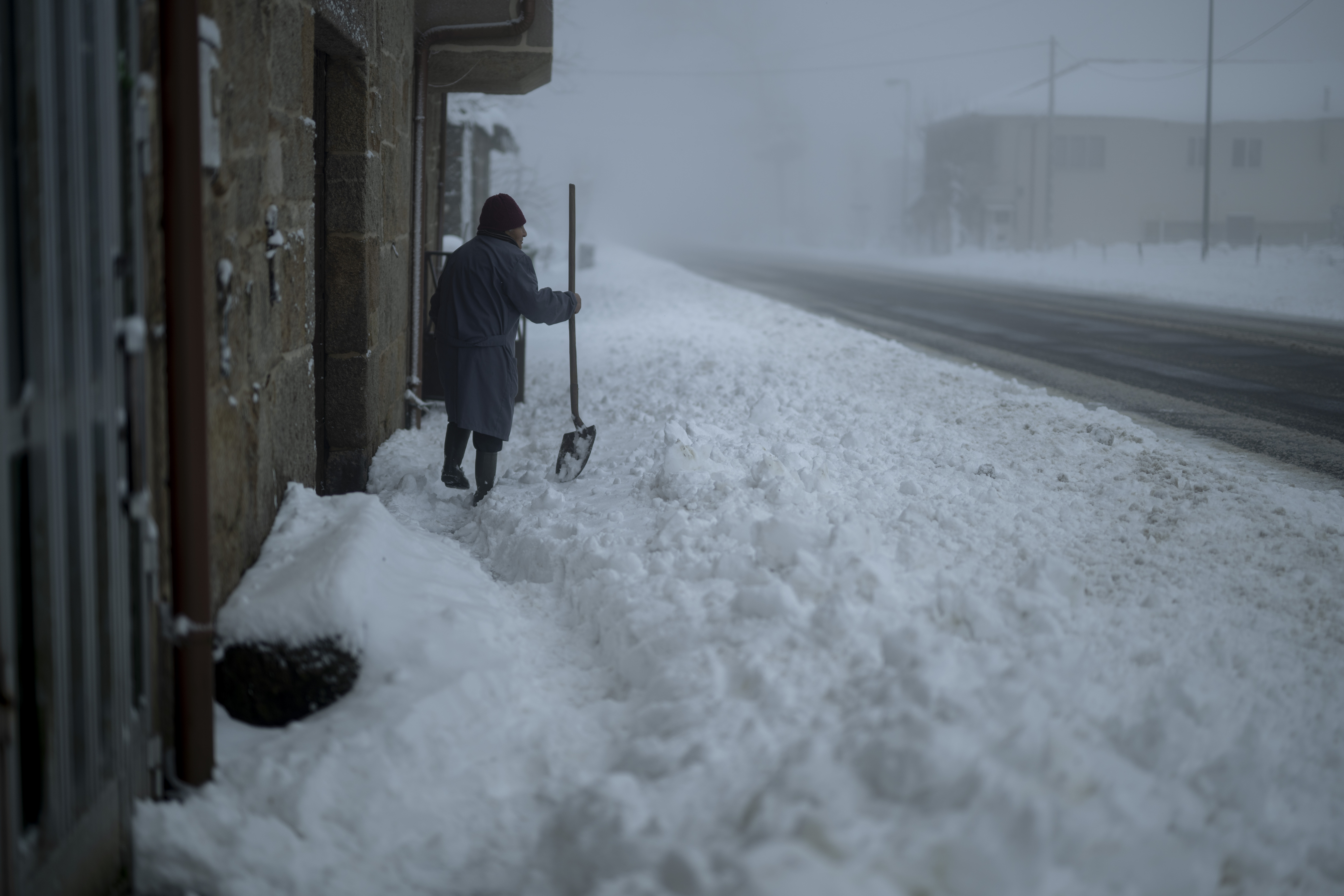 Una mujer retira nieve con una pala en la localidad de Casetas do Rodicio, Maceda (Ourense), este sábado. La borrasca Ingrid continúa en el país dejando nevadas en cotas muy bajas, tormentas en muchos puntos de la península y grandes olas en las costas del norte, además de en Canarias y en zonas de Almería. EFE/Brais Lorenzo