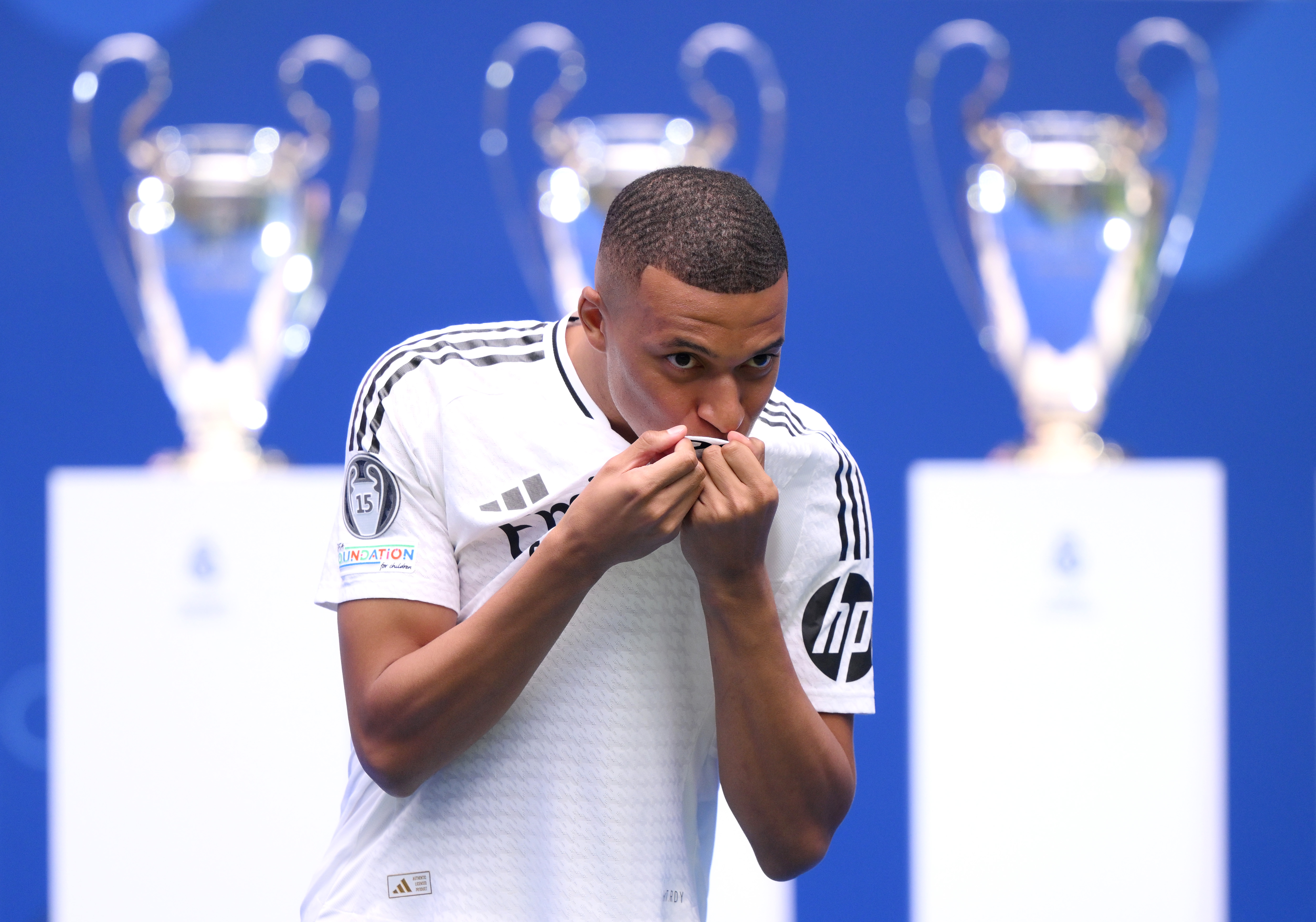 MADRID, SPAIN - JULY 16: Real Madrid new signing, Kylian Mbappe kisses the Real Madrid badge as he is unveiled at Estadio Santiago Bernabeu on July 16, 2024 in Madrid, Spain. (Photo by David Ramos/Getty Images)