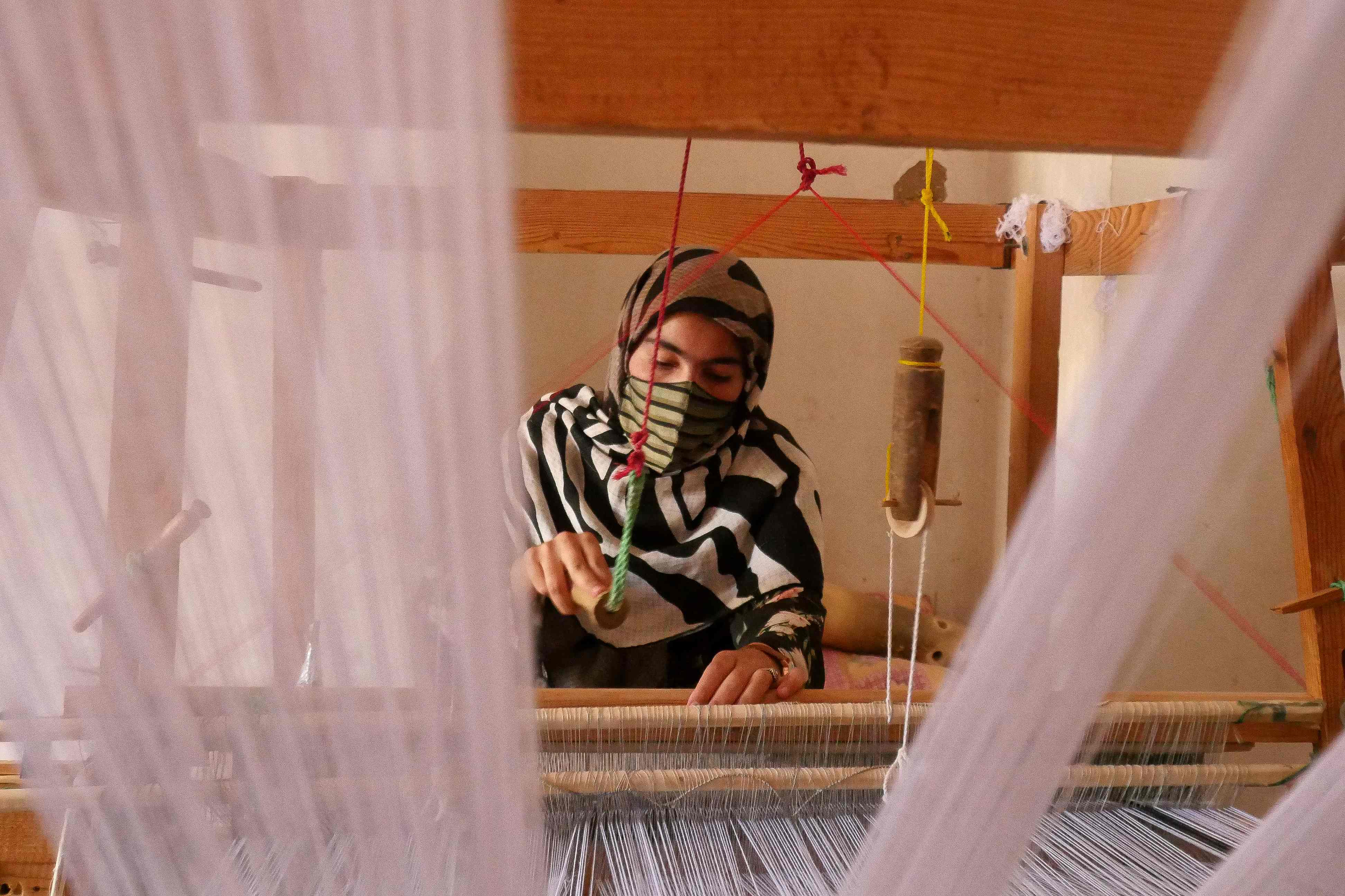 An Afghan women weaves silk to make scarfs and other products inside a workshop in the Zandajan district of Herat province. Many Afghan girls fear the longer they stay away from school, the more pressure will build to conform to patriarchal standards and marry. AFP