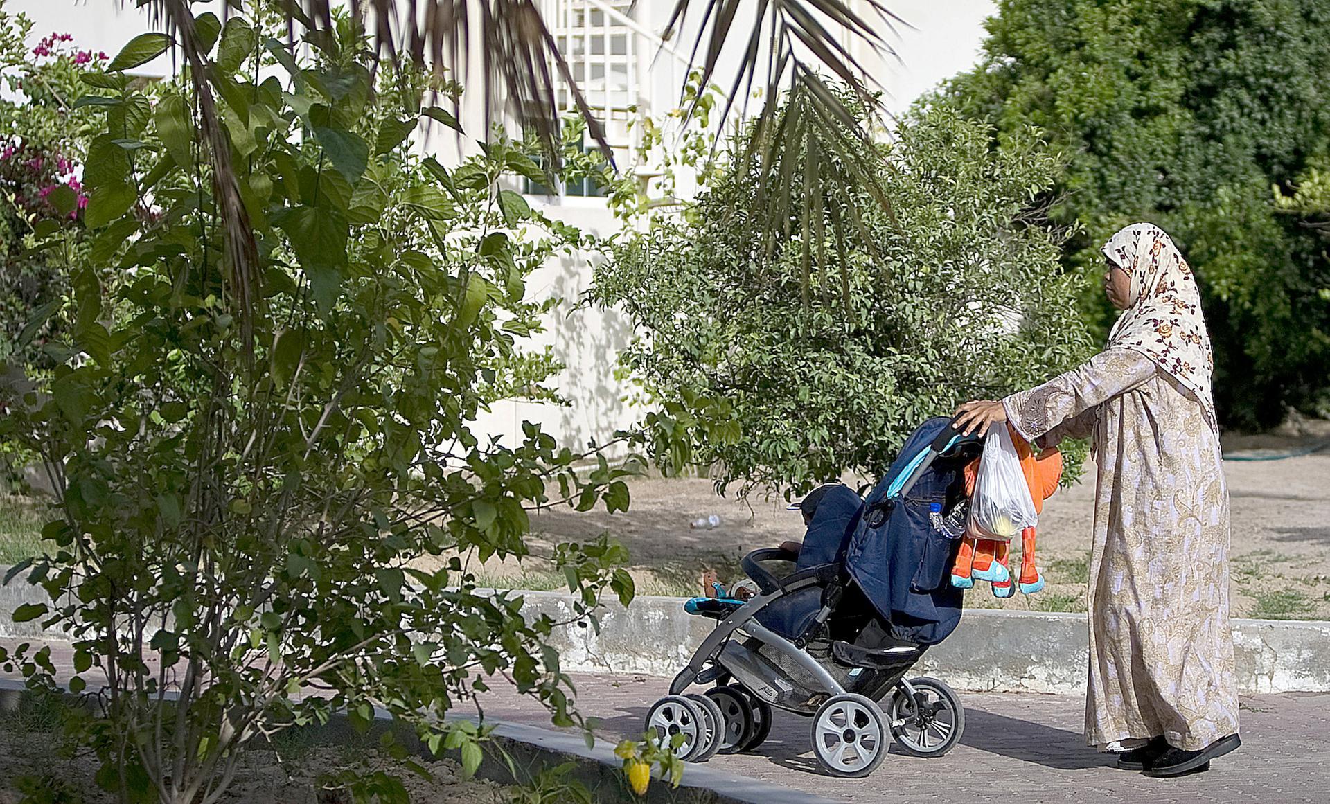 A domestic worker takes a child out for a stroll in the Nad Al Sheba neighbourhood in Dubai. The National
