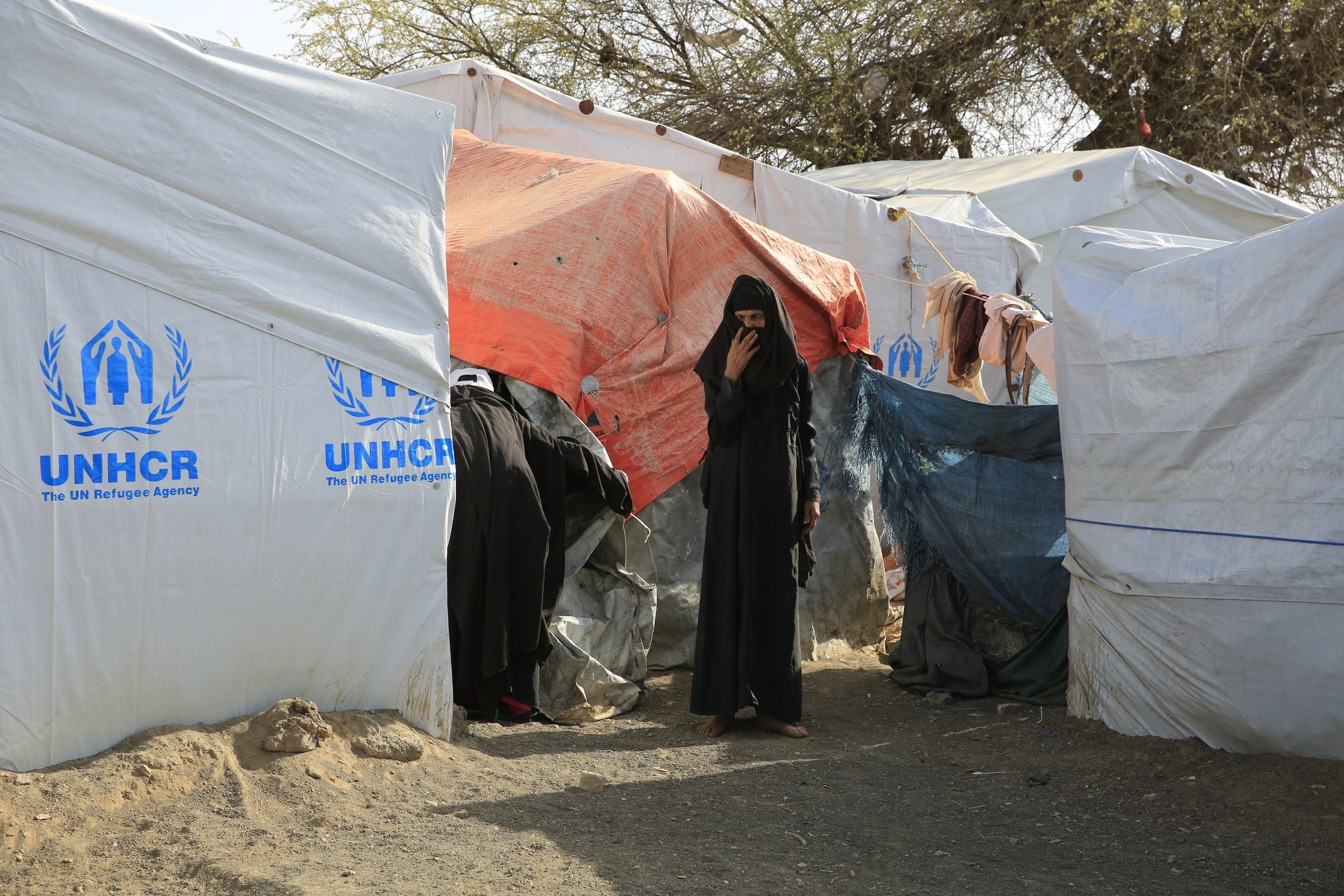 A Yemeni woman stands next to makeshift shelters at a camp for displaced people on the outskirts of Sanaa. EPA