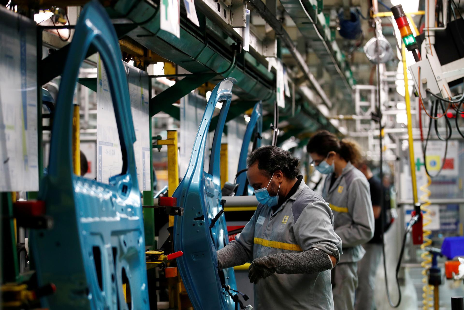 Employees, wearing protective face masks, work on the automobile assembly line of Renault Zoe cars at a factory in Flins. Reuters