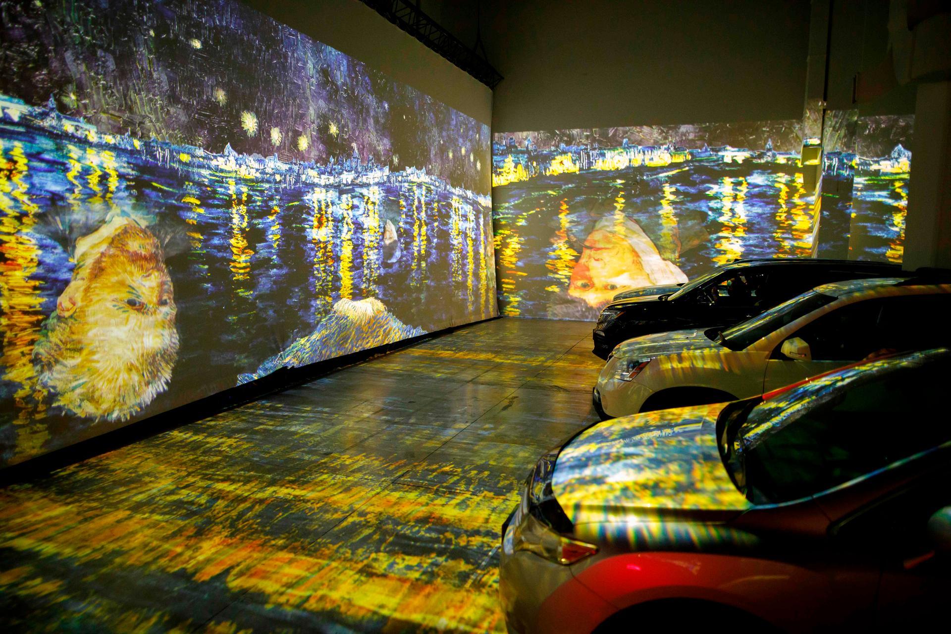People sit in their cars as they experience a drive-in immersive Vincent Van Gogh art exhibit. AFP