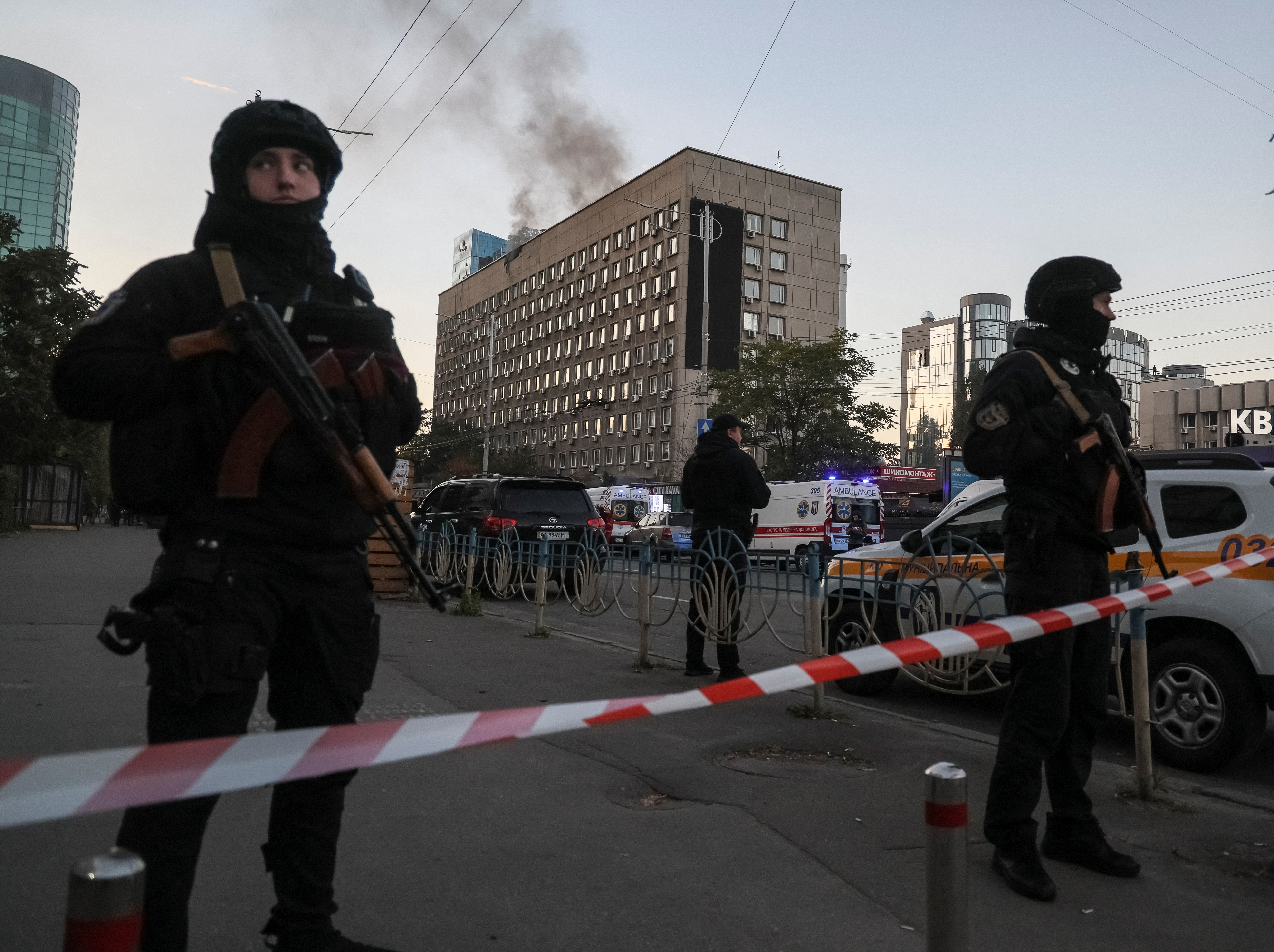 Police stand guard as smoke rises from buildings. Reuters