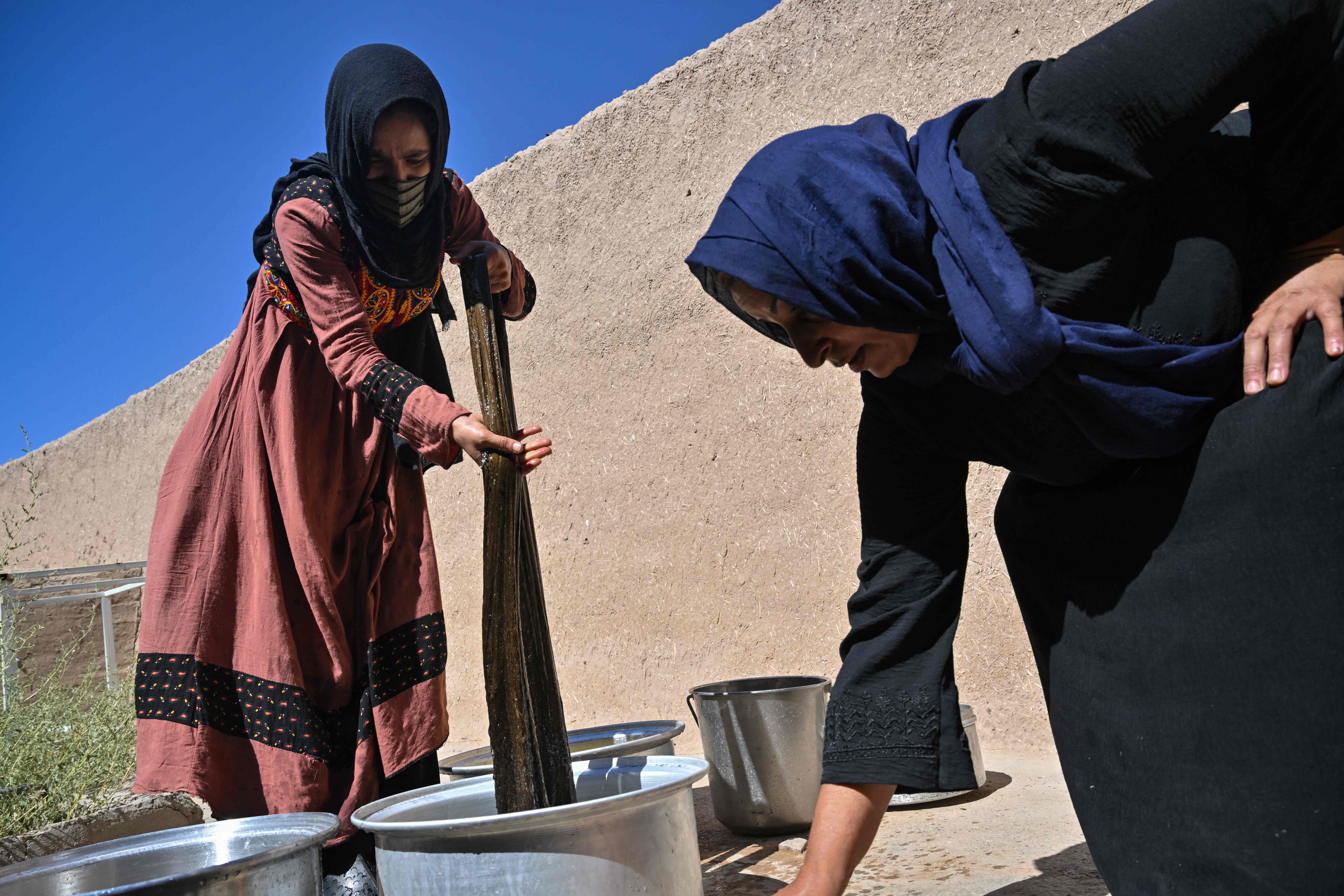 Women wash freshly dyed silk in a factory in Herat province. Whether Afghan girls receive an education under the Taliban is turning into an issue of wealth, young women living under the regime say. AFP