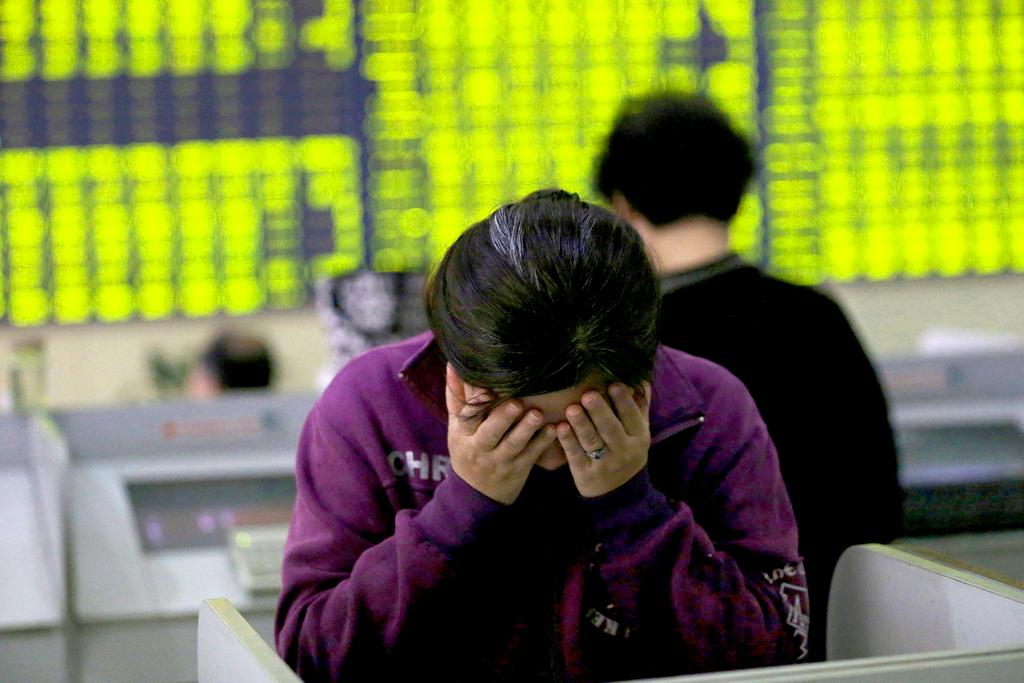 More than 30 per cent has been knocked off the value of Chinese shares since mid-June. Above, a retail investor rubs her face as she stands at a computer terminal in a brokerage house. Chinatopix via AP